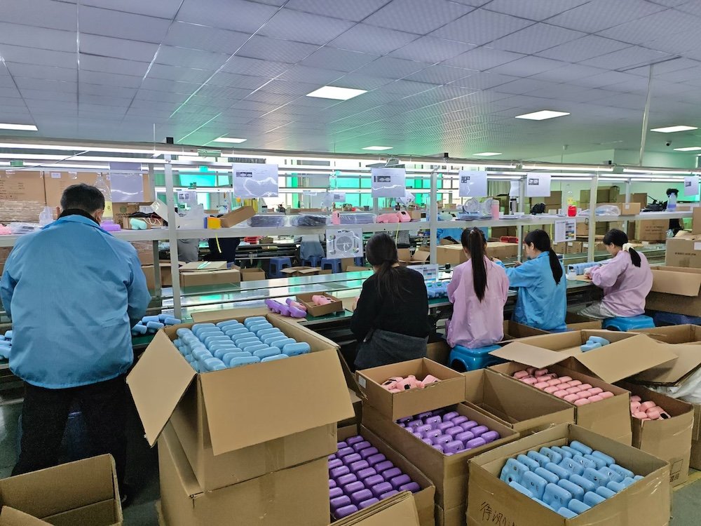 Workers of company working on the production line, packing kids cameras for clients.